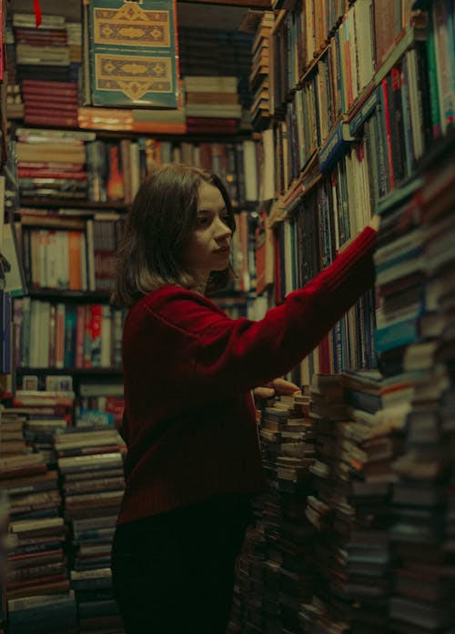 A woman in red sweater standing in front of a wall of books