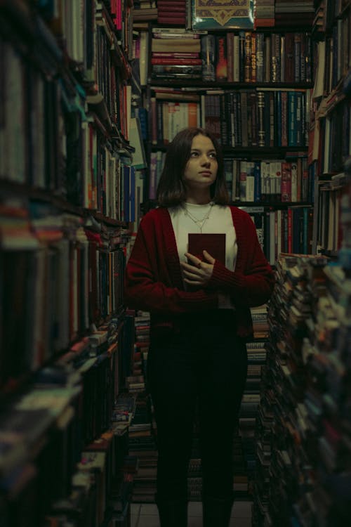 A woman standing in a library holding a book
