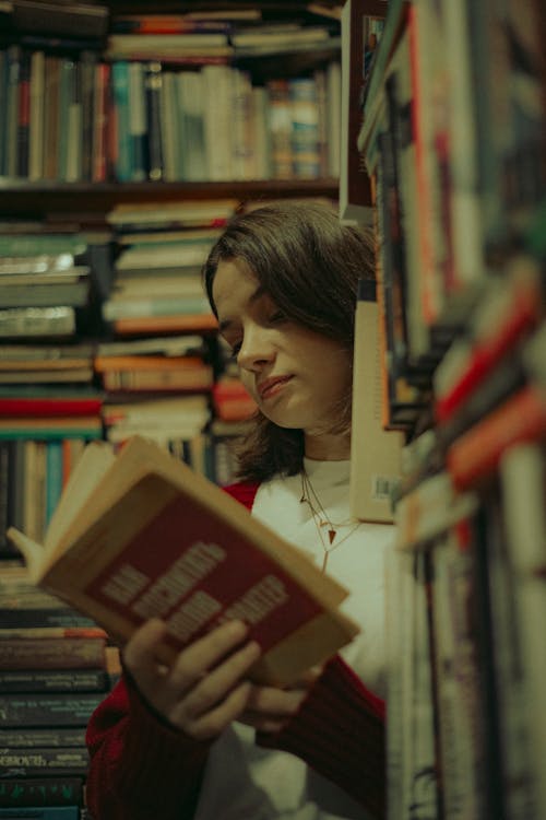 A woman is reading a book in a library