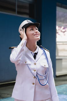 Smiling woman in a naval officer uniform looks up with confidence outdoors.