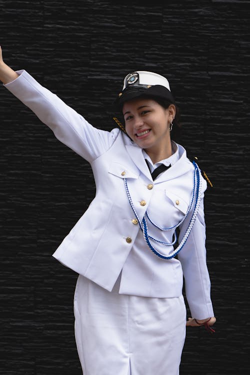 A woman in a white uniform is waving