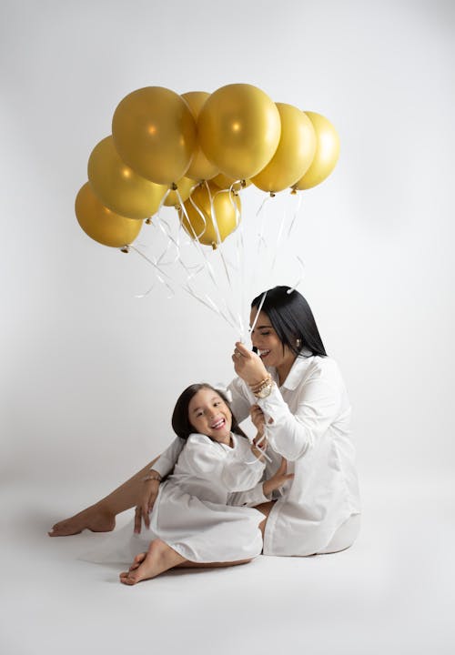 A woman and her daughter are holding balloons