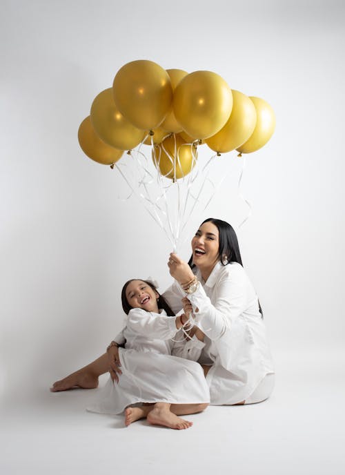 A woman and her daughter are holding balloons