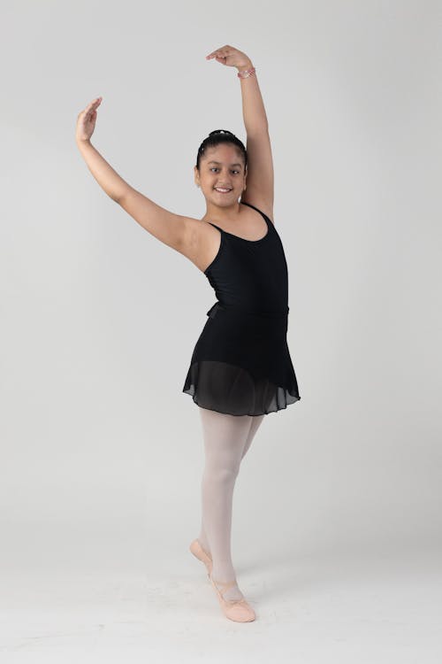 A young girl in a black tutu and ballet shoes