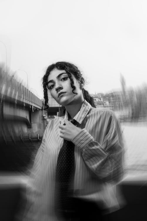 A woman in a tie and shirt is standing in front of a building