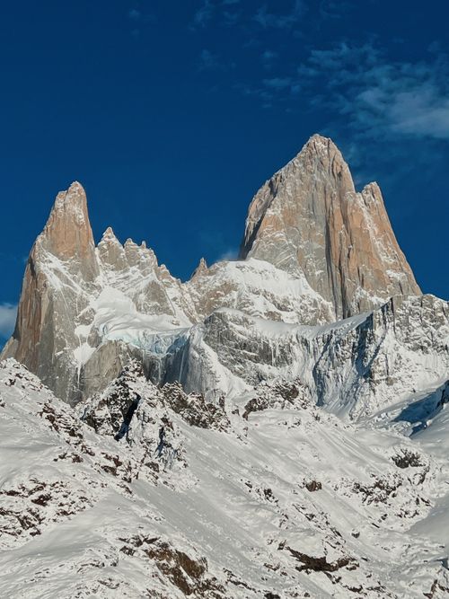 Free Stunning view of snow-covered peaks and cliffs under a clear blue sky, perfect for nature enthusiasts. Stock Photo