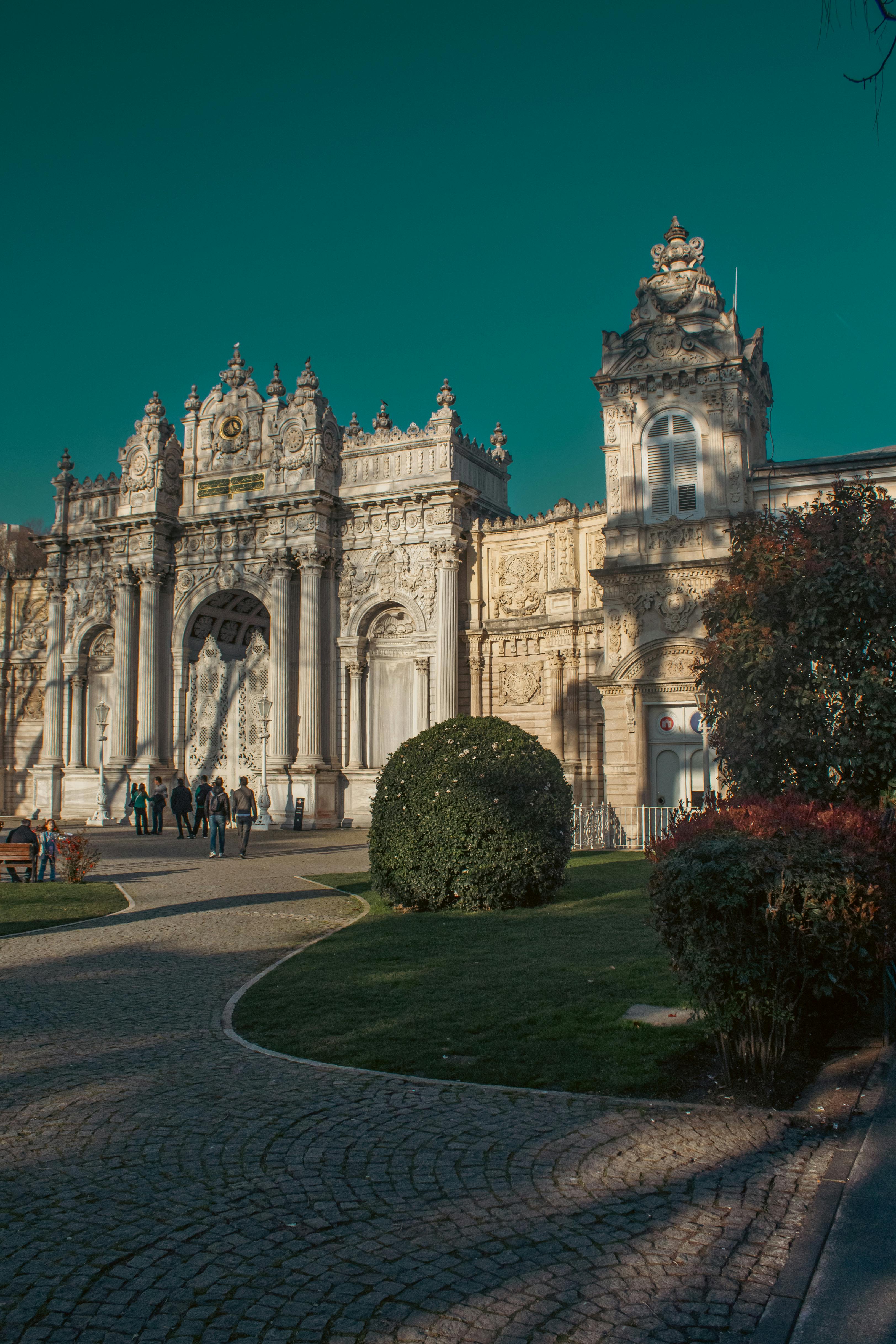 Majestic view of the Dolmabahçe Palace entrance with blue sky and garden.