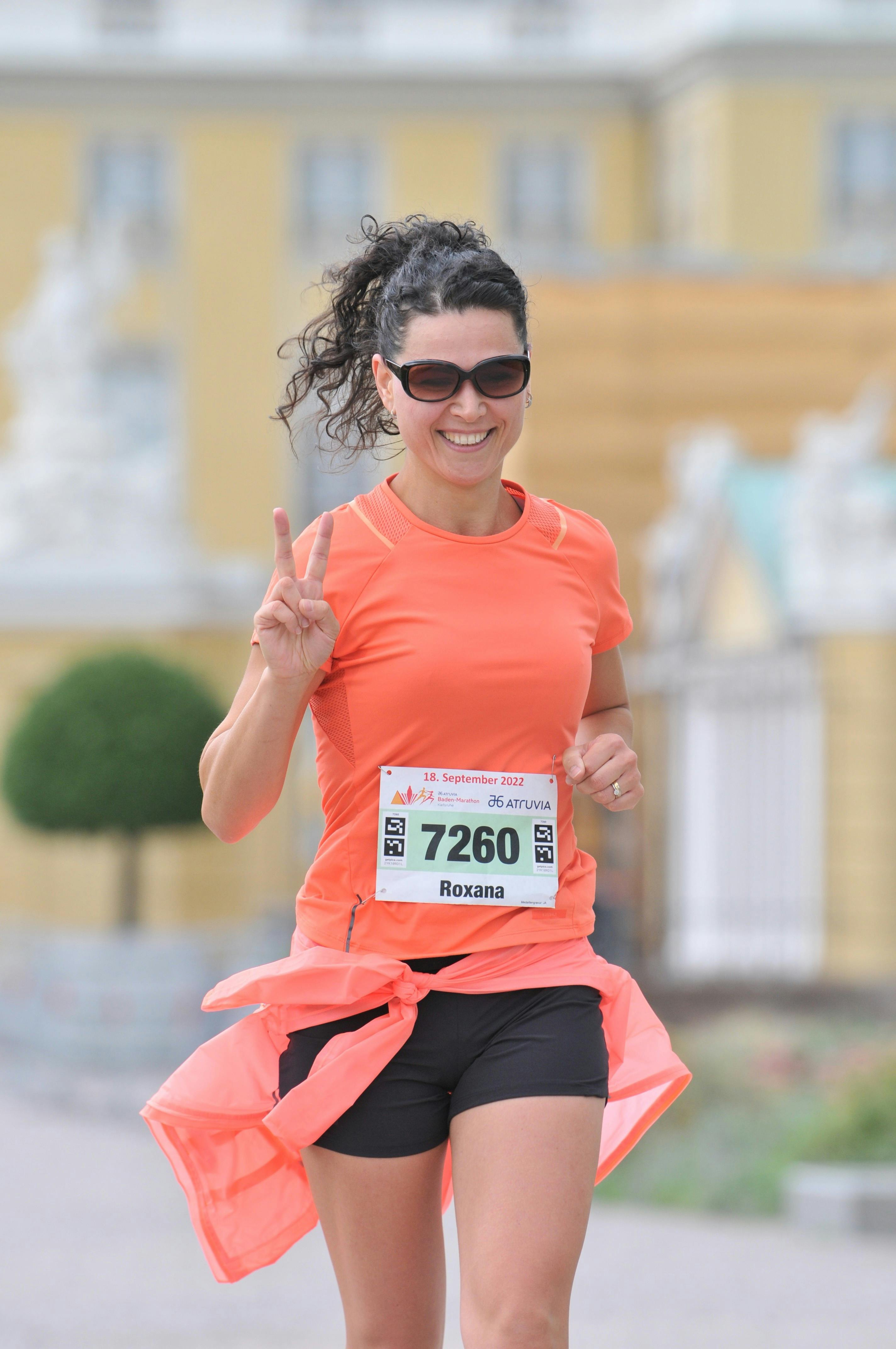 Smiling woman in orange during marathon in Karlsruhe, Germany.