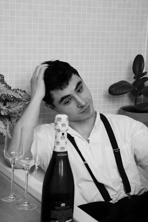 A man sitting in a bathtub with a bottle of champagne