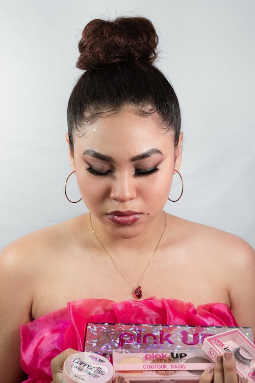 A woman in a pink dress holding a makeup kit