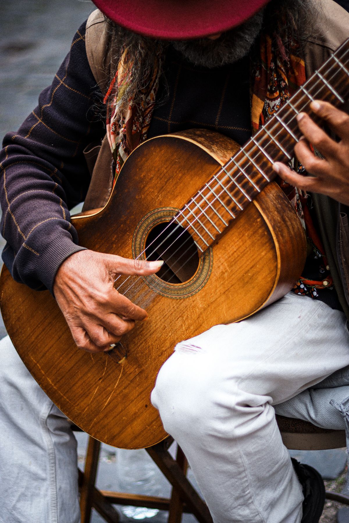 Older musician's hands playing a wooden guitar