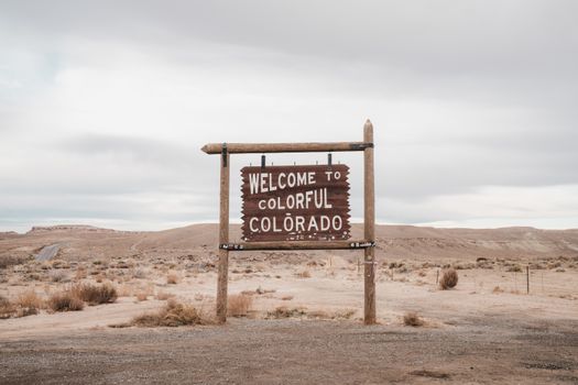Desolate landscape in Colorado featuring a rustic welcome sign, ideal for travel themes.