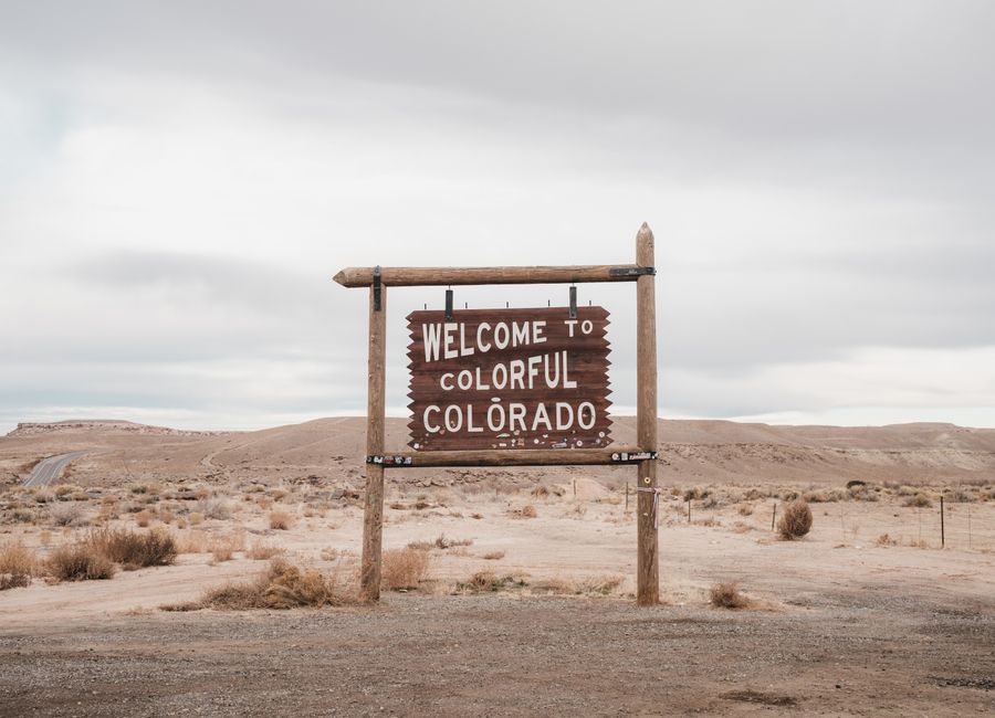 Desolate landscape in Colorado featuring a rustic welcome sign, ideal for travel themes.