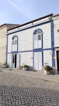 Explore a picturesque urban street featuring a classic blue and white facade with cobblestones.