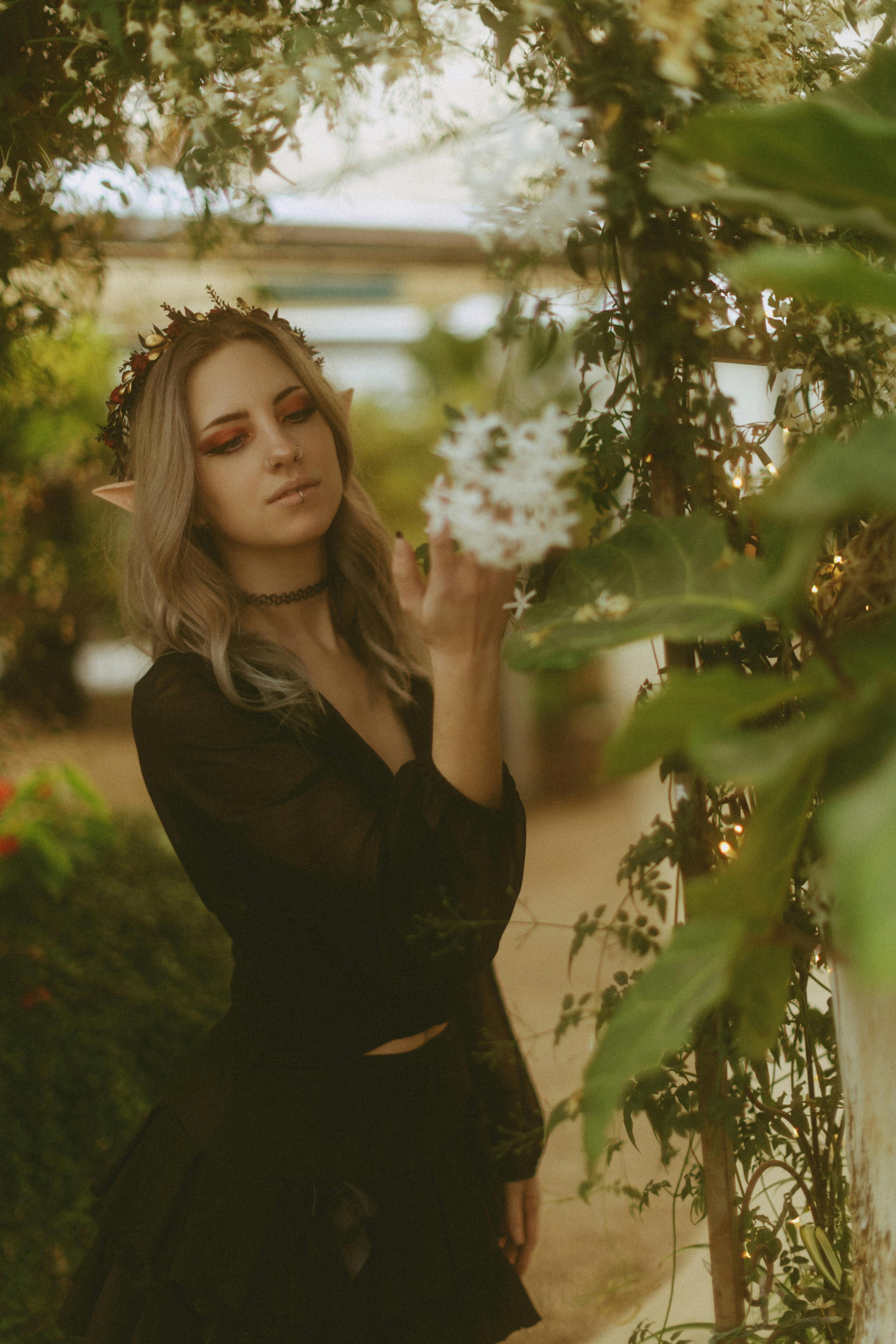 Mystical portrait of a woman with elf ears enjoying nature in a garden.