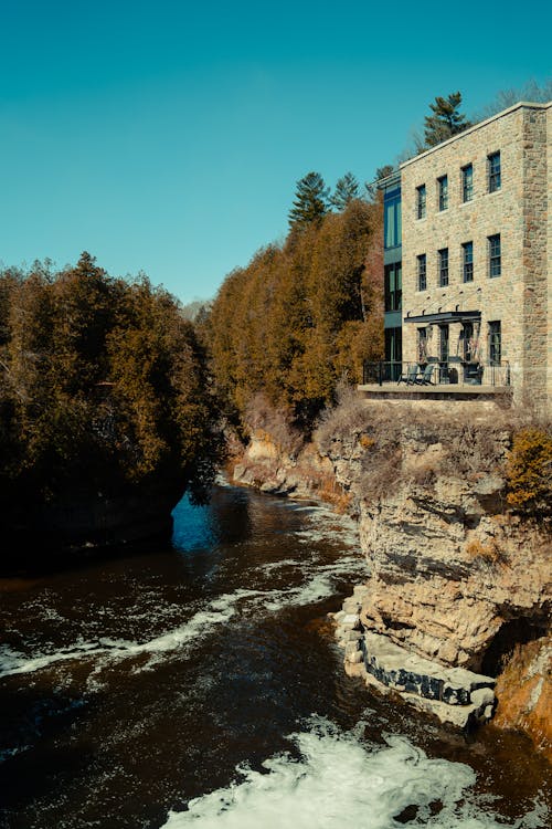 A building sits on top of a cliff next to a river