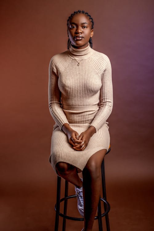 A woman in a beige sweater sitting on a stool