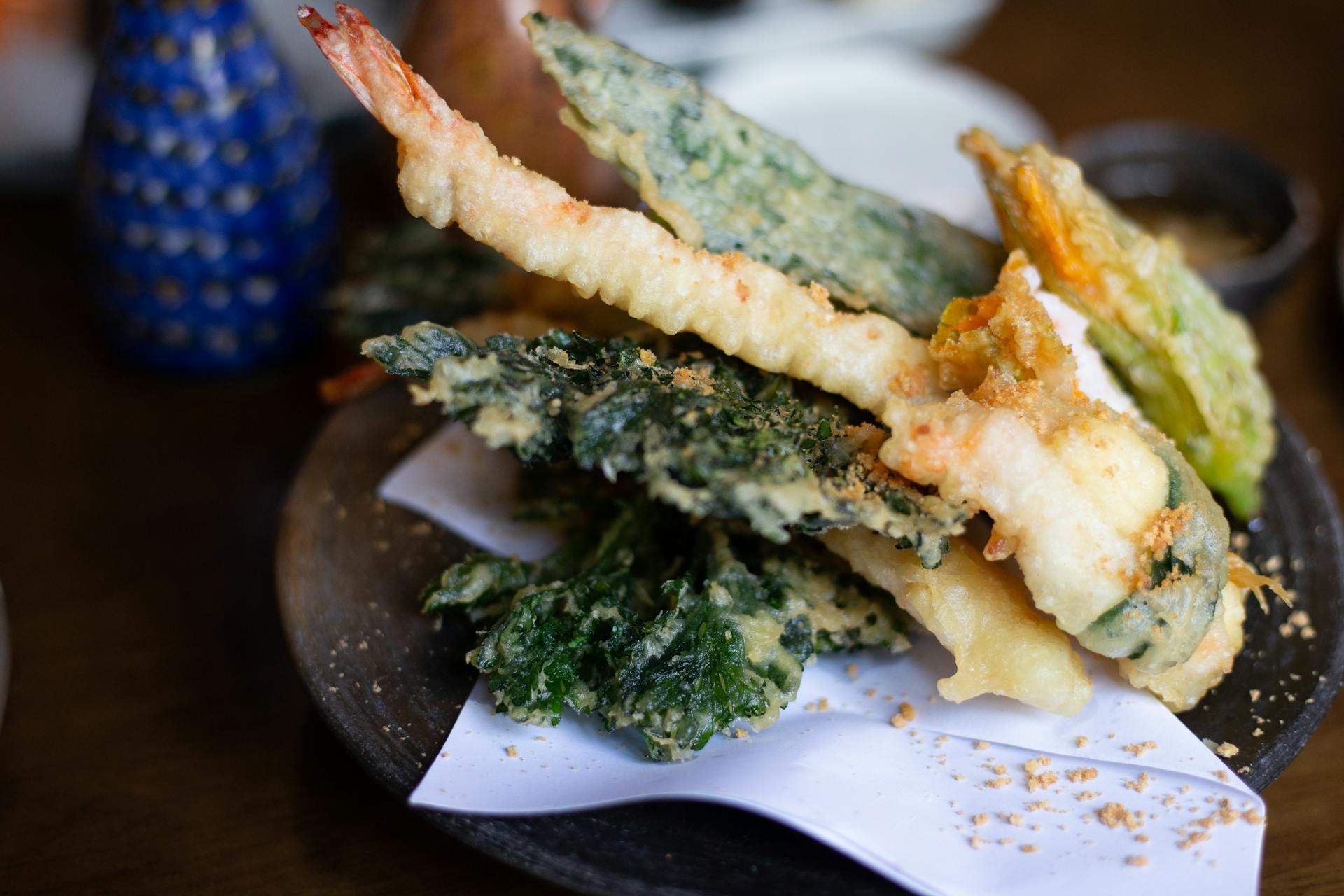 Deliciously prepared Japanese tempura featuring shrimp and vegetables on a dark plate.