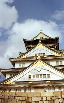 Majestic view of Osaka Castle under a vibrant blue sky, showcasing traditional Japanese architecture.