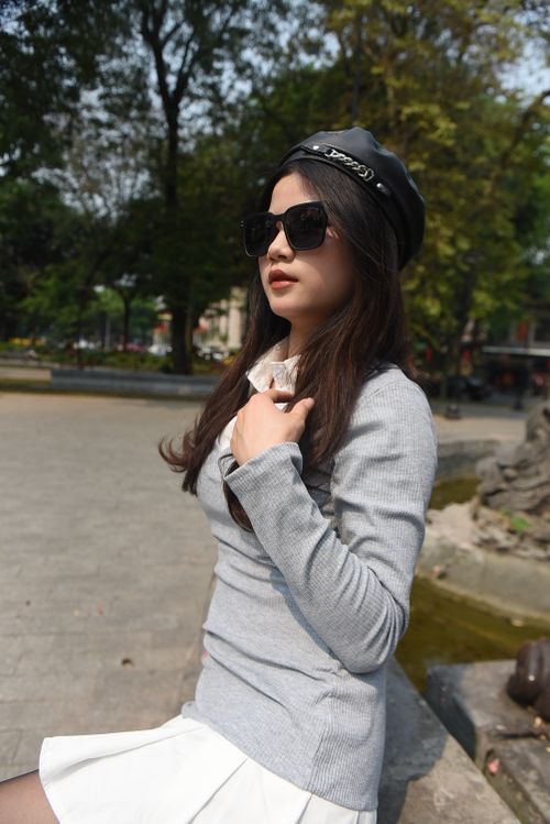 Free Stylish Asian woman with sunglasses and hat sitting in a sunny urban park. Stock Photo
