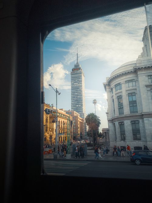 Free View of Torre Latinoamericana through a window in vibrant Ciudad de México, capturing urban life. Stock Photo