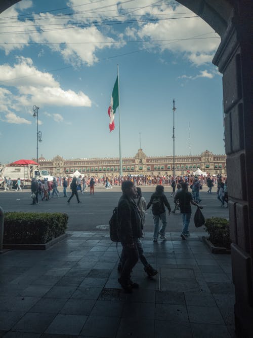 People walking through an archway with a mexican flag