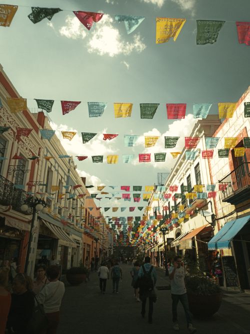 Free A bustling urban street in Ciudad de México adorned with colorful flags under a sunny sky. Stock Photo