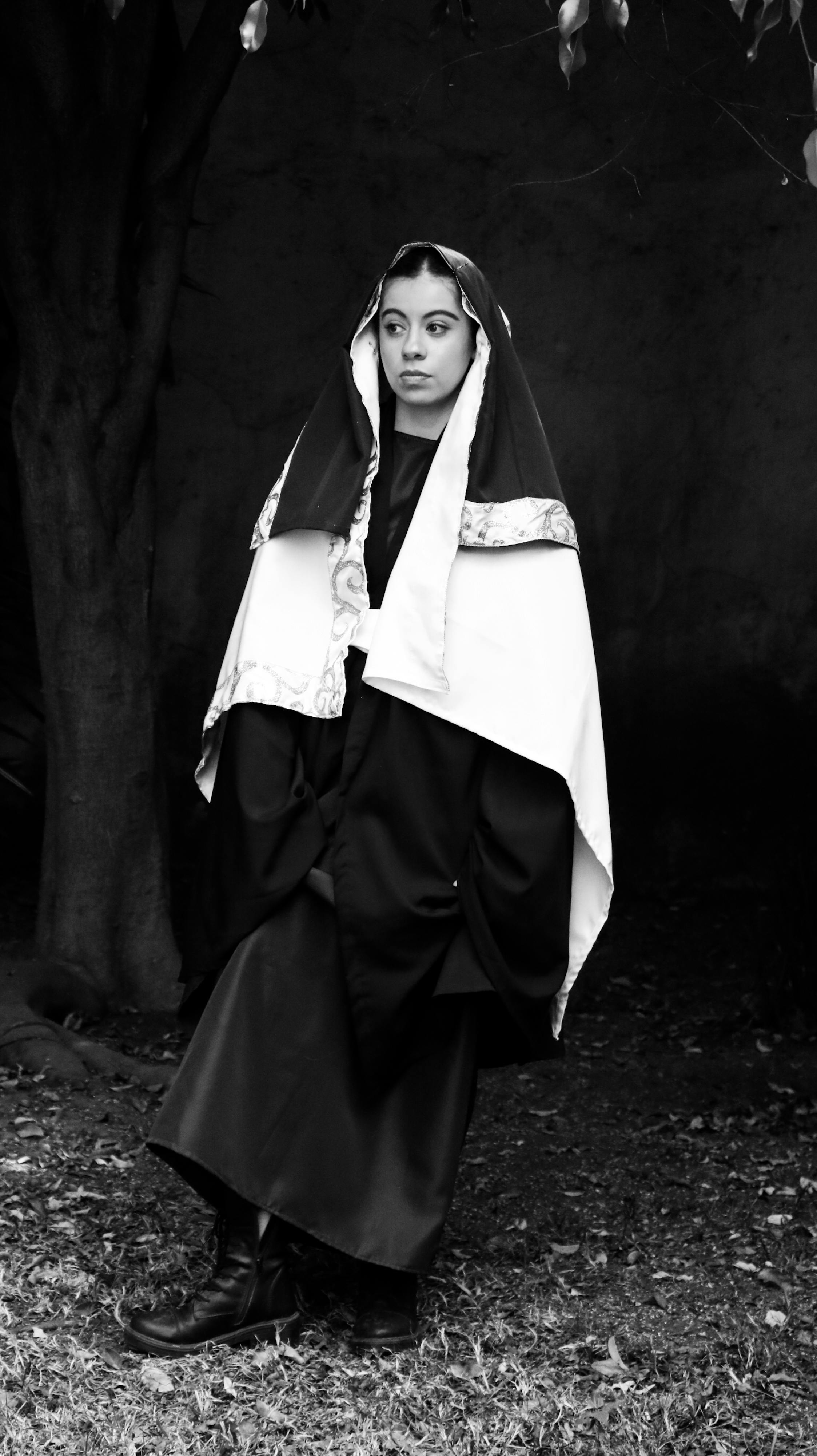 A striking black and white portrait of a woman in a gown, outdoors, capturing a timeless fashion moment.