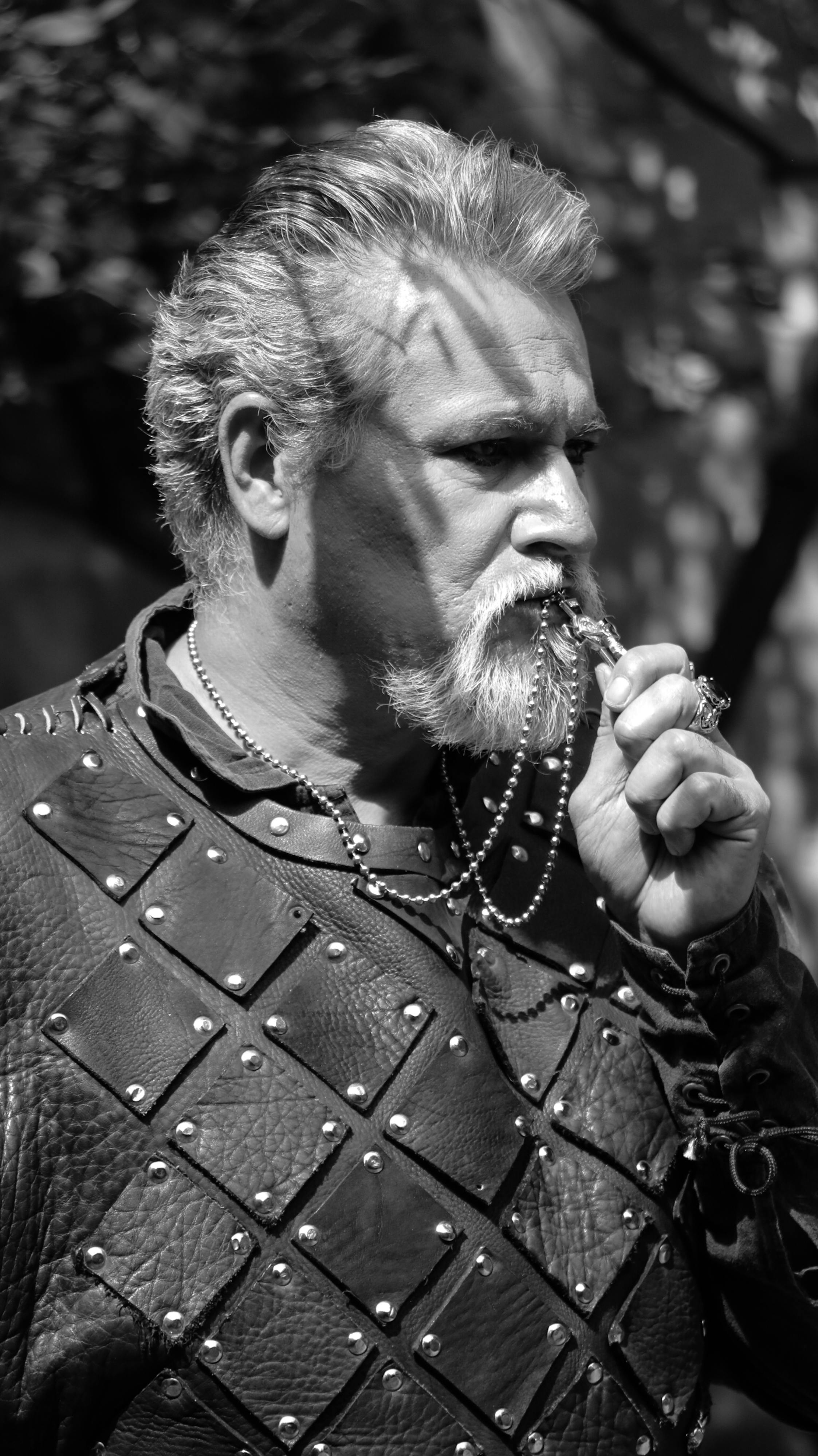 Portrait of a bearded man in leather armor holding a pendant, in black and white.