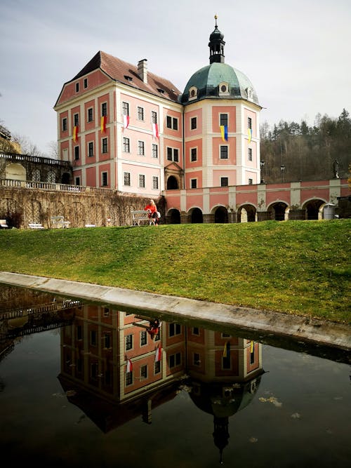 A pink building with a reflection in the water