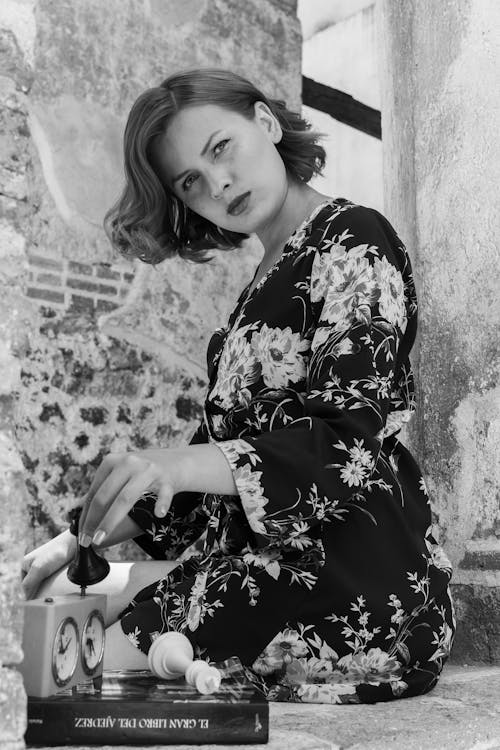 A woman in a floral dress is sitting on a bench