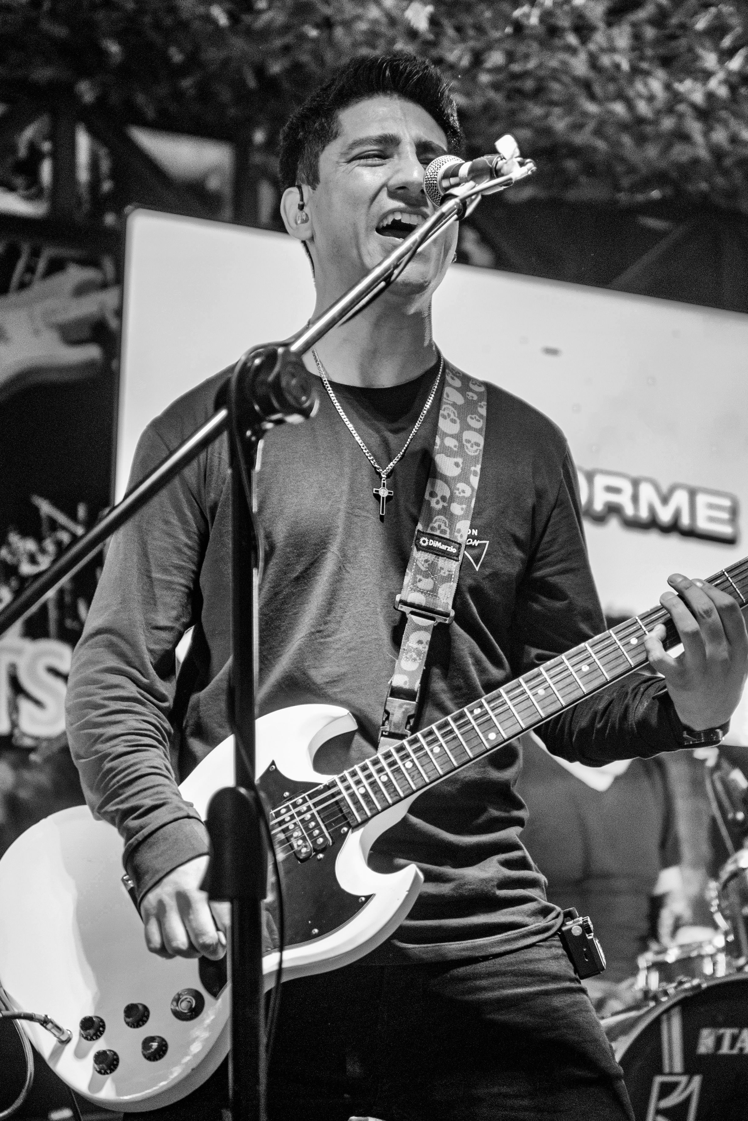Dynamic black and white photo of a guitarist singing passionately on stage in Lima, Peru.