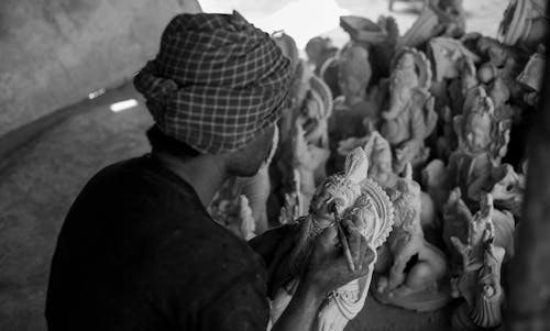 A black and white photo of a man making sculptures