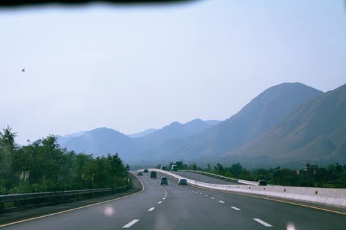 Free Experience a serene drive through mountain highways with clear blue skies and lush greenery. Stock Photo