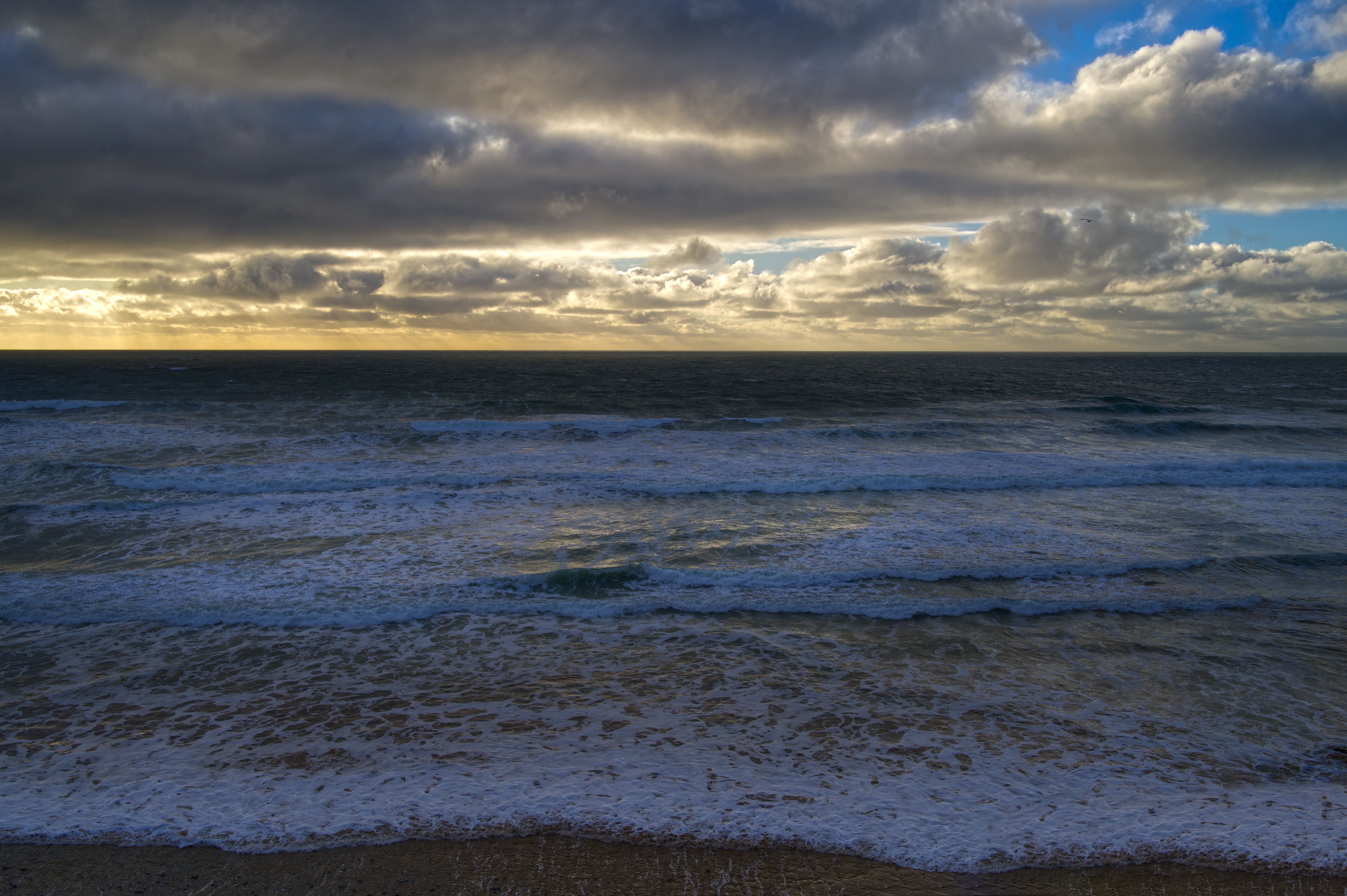 A cloudy sky with a beach and ocean · Free Stock Photo