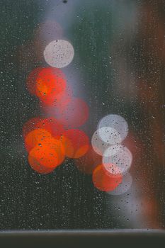 Raindrops on a window with colorful bokeh in Jakarta, Indonesia.