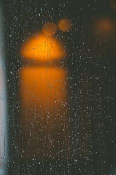 Artistic view of raindrops and blurred city lights through a window pane.