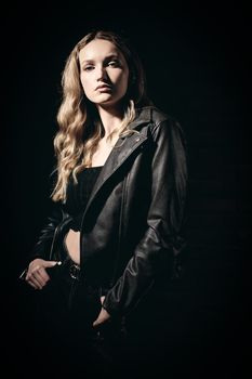Fashion model wearing a leather jacket, showcasing a punk-inspired style in dramatic lighting.