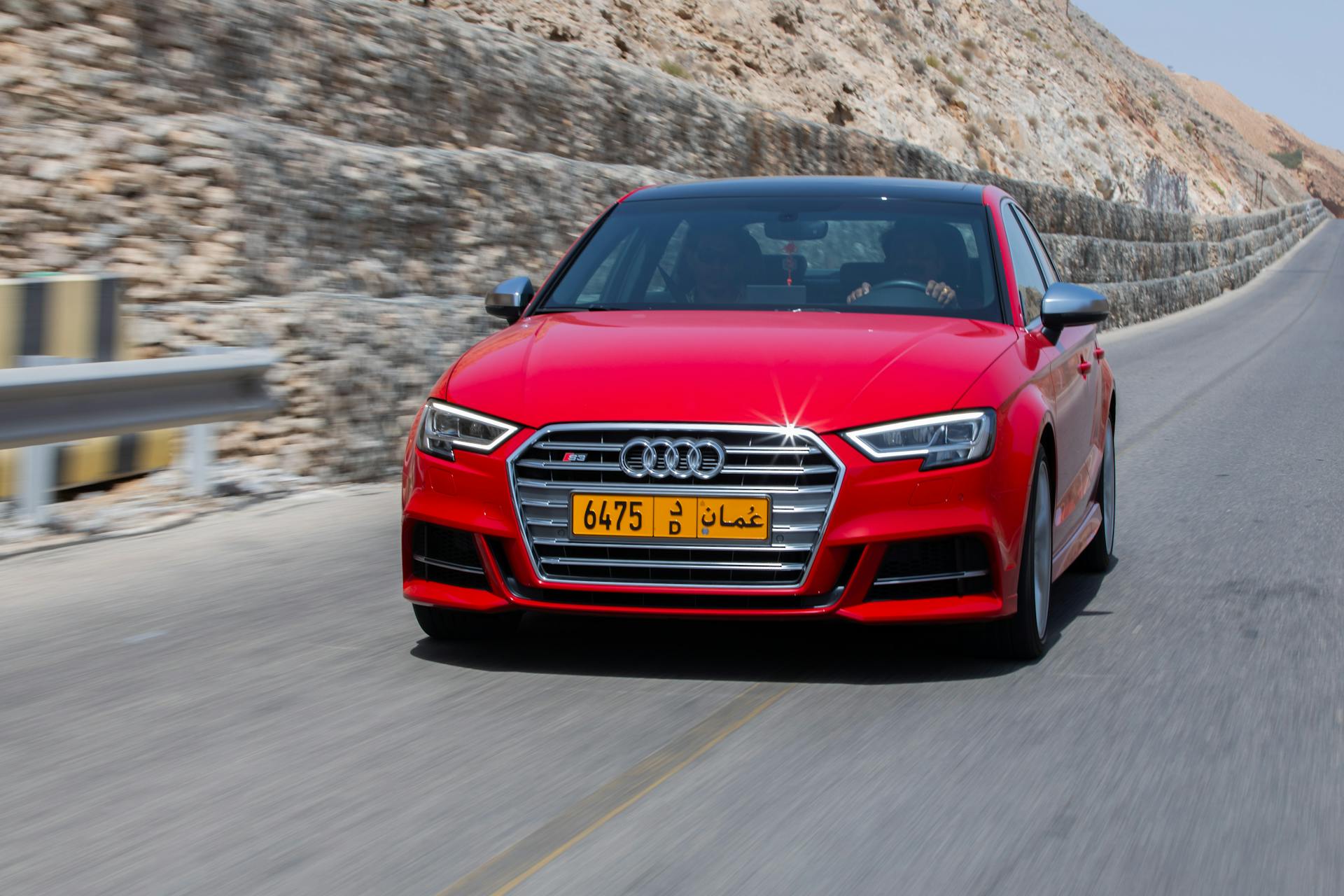 A dynamic shot of a red Audi S3 driving on a mountain road in Muscat, Oman.