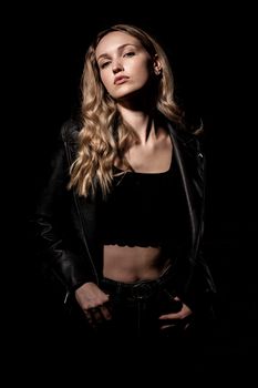 Stylish portrait of a young woman posing confidently in a leather jacket against a dark background.
