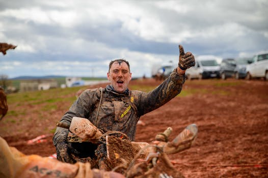 Happy motocross rider gives thumbs up after muddy ride on a challenging outdoor track.