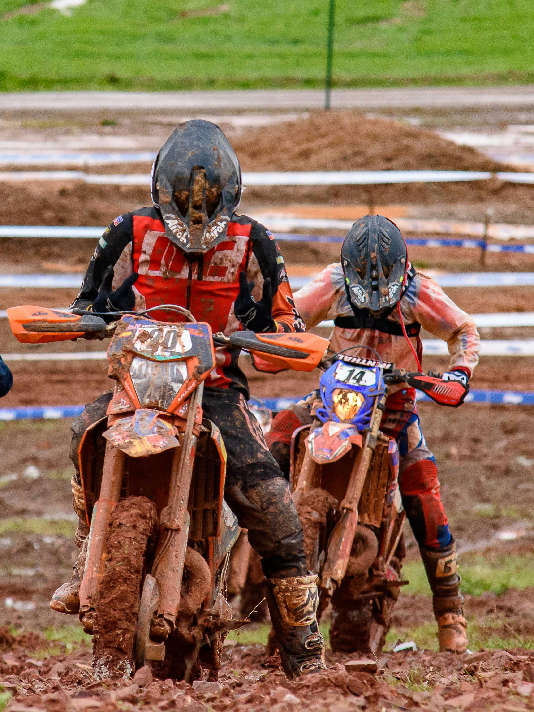 Two motocross riders racing through a muddy track showcasing skill and adrenaline.