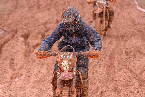 Two people riding dirt bikes on a muddy trail