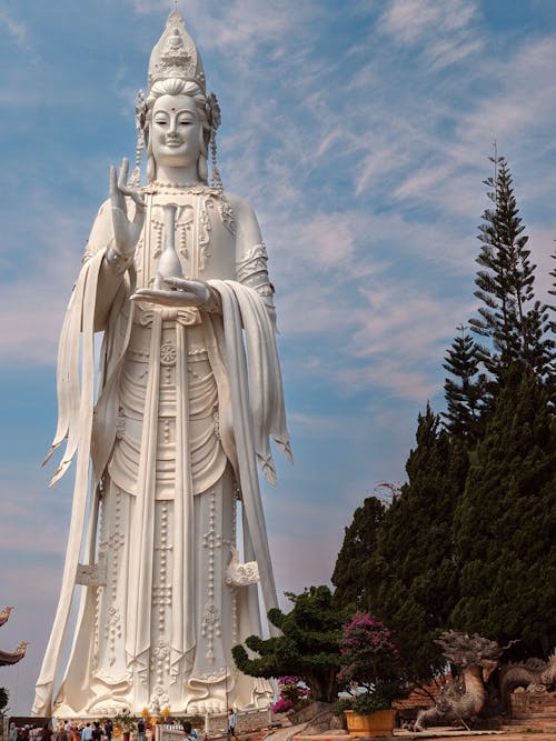 A large statue of a buddha in front of a tree