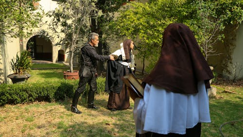 Elderly Man Grabbing Arm of Nun in Garden
