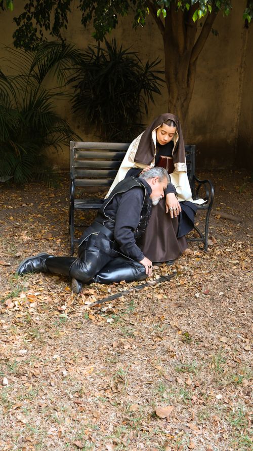 Free A medieval knight rests on a nun's lap on a park bench surrounded by autumn leaves. Stock Photo