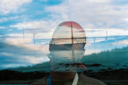 Free A man is looking at the sky with a bridge in the background Stock Photo