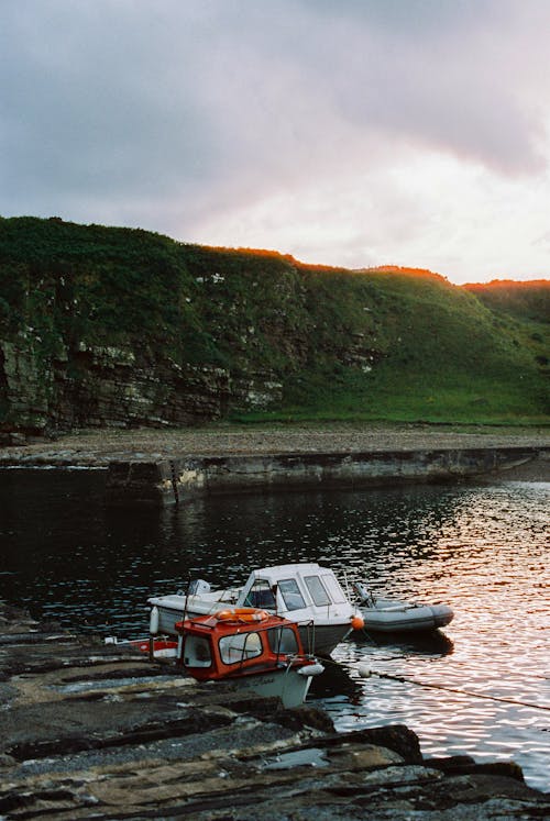 A boat is docked on a rocky shore at sunset