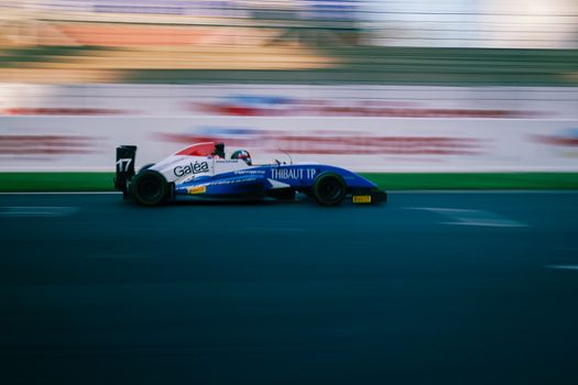 High-speed racing car on a circuit track showcasing motion blur and vibrant colors.