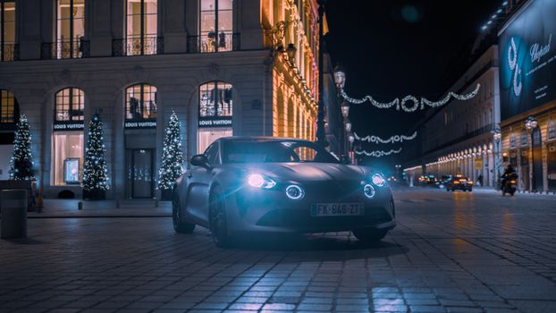 Luxury Alpine A110 showcased on illuminated city streets at night, exuding elegance and style.